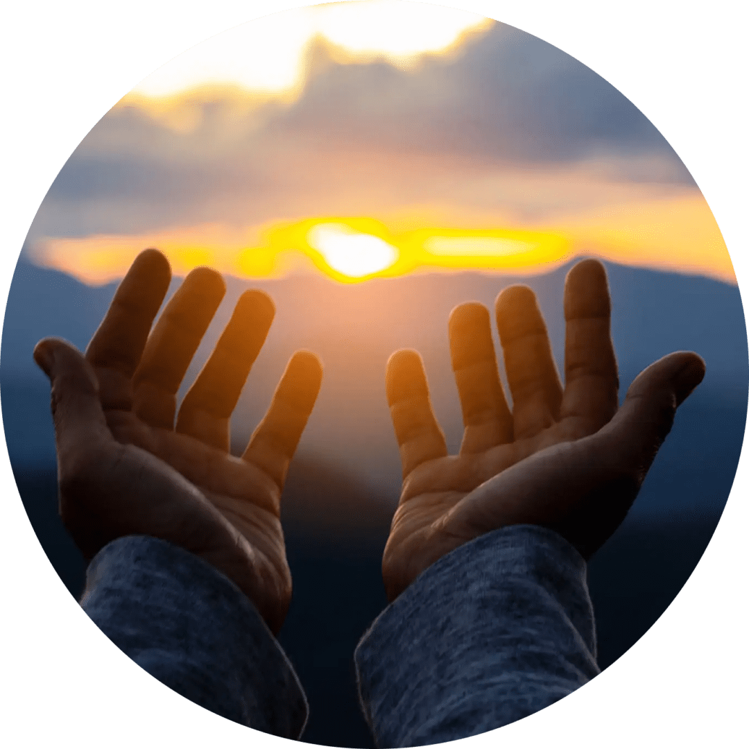 Hands reaching out to a glowing sunset in a serene landscape.