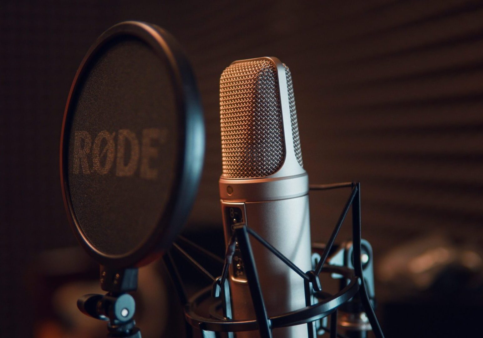 Close-up of a professional condenser microphone with pop filter in a recording studio.